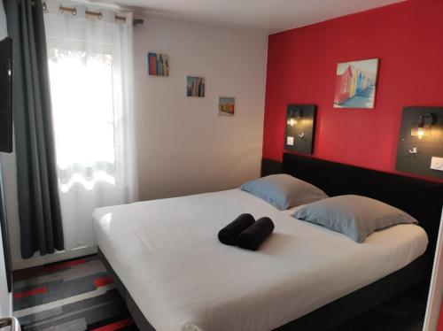 a bedroom with a bed with two black objects on it at Kyriad Direct Saintes in Saintes