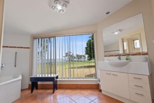 Un baño con lavabo y una gran ventana. en Steamer - Waterfront Retreat, en Goon Nure