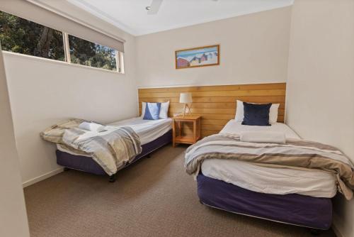 Dos camas en una habitación con dos ventanas. en Steamer - Waterfront Retreat, en Goon Nure
