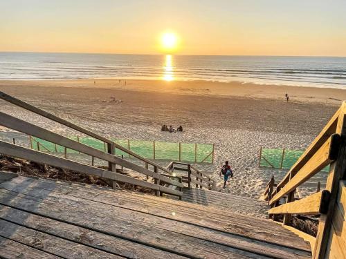 a view of a beach at sunset with a wooden boardwalk at Apartment L'Oustalet-6 by Interhome in Mimizan