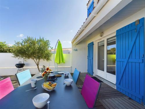 une terrasse avec une table, des chaises et un parasol dans l'établissement À 550m de la plage, jolie maison pour 5, à Plage-des-Demoiselles
