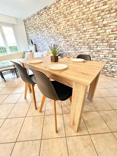 une table en bois avec des chaises et un mur en briques dans l'établissement Le bijou d'Ivelina - 3 chambres - wifi - parking, à Chartres