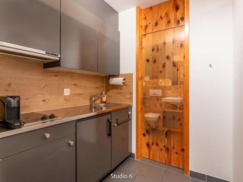 eine Küche mit einem Waschbecken und einer Holzwand in der Unterkunft Apartment Steil Alva Studios Smit by Interhome in Lenzerheide