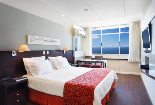 um quarto de hotel com uma cama e uma grande janela em Sol Ipanema Hotel no Rio de Janeiro