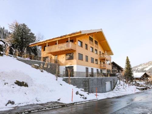 a house on a snow covered hill next to a road at Apartment Sparenmoos - OG - DG Nord-Ost by Interhome in Zweisimmen
