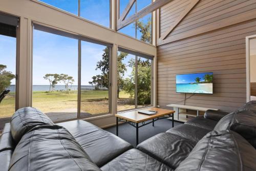 a living room with a large couch and a table at Avon - Waterfront Retreat in Goon Nure