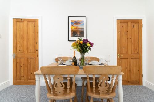 a dining room table with chairs and a vase of flowers at Bright~ Town Center~ 2 bed~Penzance in Penzance