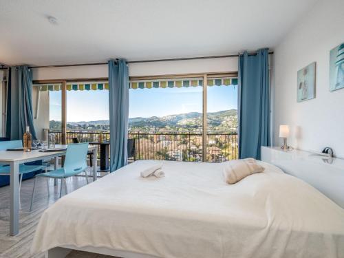 une chambre avec un grand lit et une table et des chaises dans l'établissement Apartment Le Surcouf by Interhome, à Mandelieu-la-Napoule