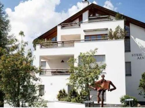 a man standing in front of a white building at Apartment Steil Alva Studios Smit by Interhome in Lenzerheide