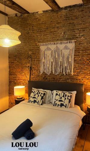 a bedroom with a large white bed with a brick wall at LouLou Home's in Antwerp