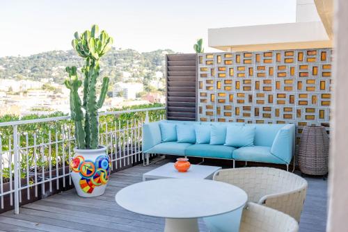 a patio with a couch and tables on a balcony at Mondrian Cannes in Cannes