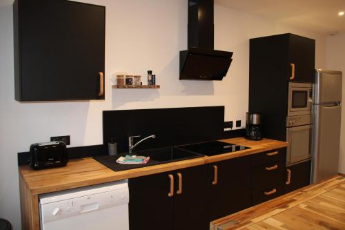a kitchen with black cabinets and a sink at Appart Côte d'Opale in Condette
