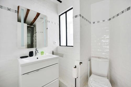 une salle de bain blanche avec un lavabo et des toilettes dans l'établissement Duplex pour 6 a Republique Confort et Centralite, à Paris