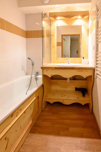 une salle de bain avec une baignoire, un lavabo et un miroir dans l'établissement CozyLoge, Orelle & Les 3 vallées, à Orelle