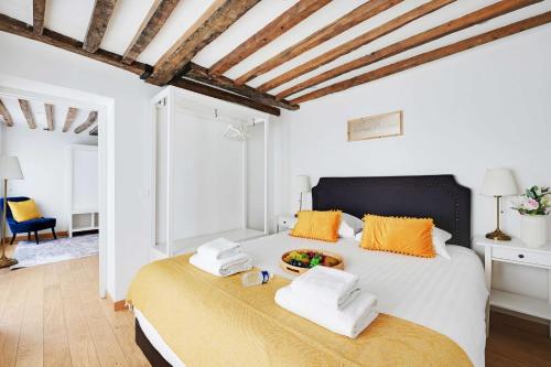 - une chambre blanche avec un grand lit et des oreillers orange dans l'établissement Duplex pour 6 a Republique Confort et Centralite, à Paris