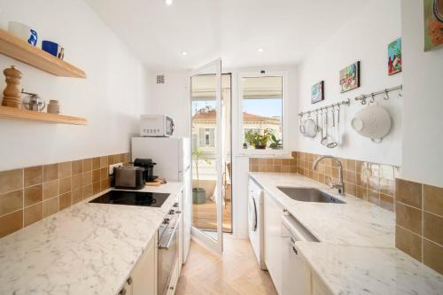 La cuisine est équipée de comptoirs blancs et d'un réfrigérateur. dans l'établissement REF 1960 - Cannes Center - Croisette, à Cannes