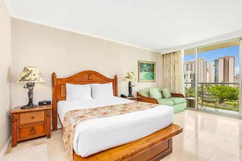 a bedroom with a bed and a chair and a window at Luana Waikiki Hotel & Suites in Honolulu