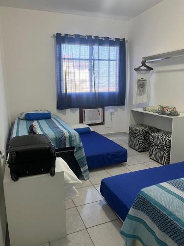 a bedroom with two beds and a suitcase in it at Novidade na Enseada Azul! Apto com churrasqueira, área gourmet e Ar condicionado a 150m da praia in Guarapari