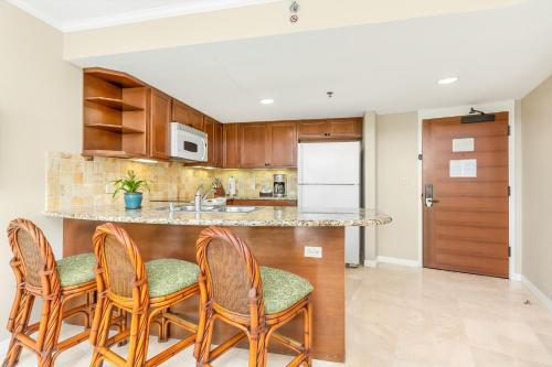 a kitchen with wooden cabinets and a counter with chairs at Luana Waikiki Hotel & Suites in Honolulu