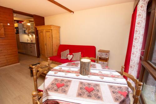 a living room with a table and a red chair at Au Doubs Refuge in Métabief