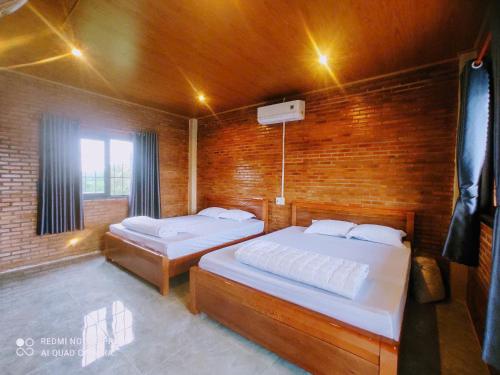 a bedroom with two beds and a brick wall at Tổ Homestay in Tân Phú