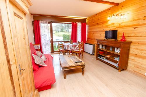 a living room with a red couch and a table at Au Doubs Refuge in Métabief