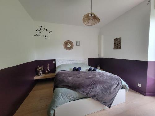 - une chambre avec un lit et une couverture violette dans l'établissement Le Chêne Loret, à Poligné