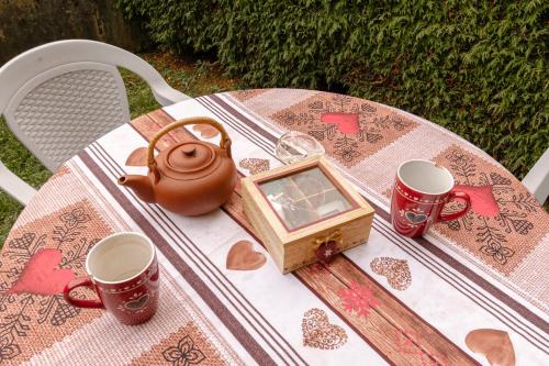 a table with a tea kettle and two cups on it at Au Doubs Refuge in Métabief