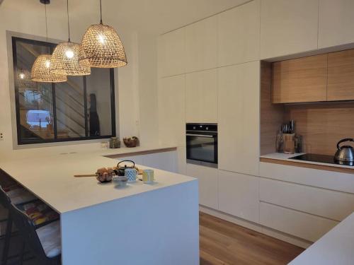 une cuisine avec un comptoir blanc et quelques lumières dans l'établissement Le Chêne Loret, à Poligné