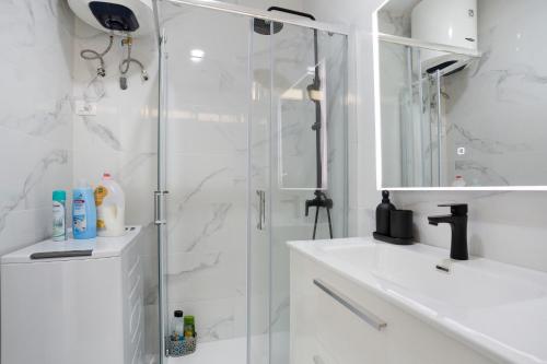 a white bathroom with a shower and a sink at Apartamento Frente Oceano in Puerto de la Cruz