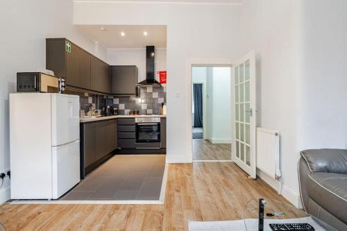 a kitchen with a refrigerator and a couch in a room at Stunning Ground Floor flat in Southside. in Glasgow
