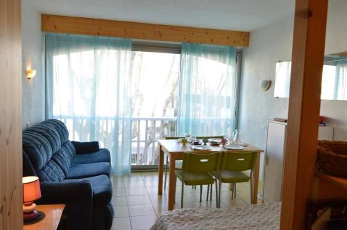 - un salon avec un canapé bleu et une table avec des chaises dans l'établissement Studio CAP D'AGDE CT090-099, au Cap d'Agde