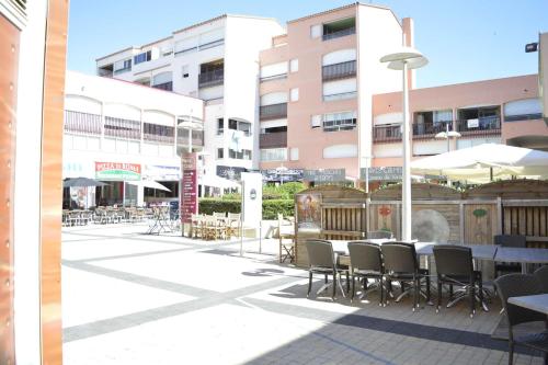 un patio extérieur avec des tables, des chaises et des bâtiments dans l'établissement Studio CAP D'AGDE CT090-099, au Cap d'Agde