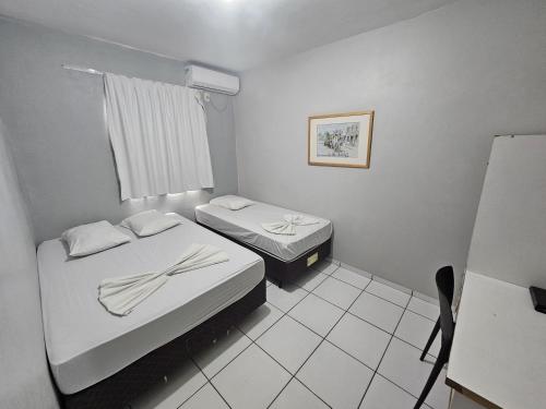 a small room with two beds and a window at Ok Inn Hotel Criciúma Centro in Criciúma