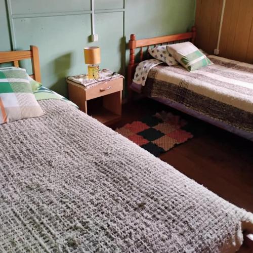 a bedroom with two beds and a table with a lamp at Hospedaje Chumaihuen in Quellón