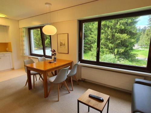 a dining room with a table and chairs and windows at Apartment Belmont Seegarten by Interhome in Lenzerheide