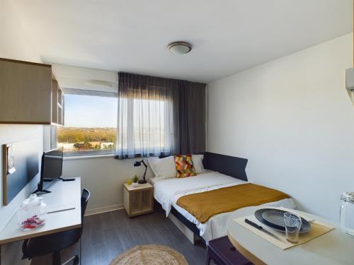 a bedroom with a bed and a desk and a window at Résidence Kley Toulouse in Toulouse