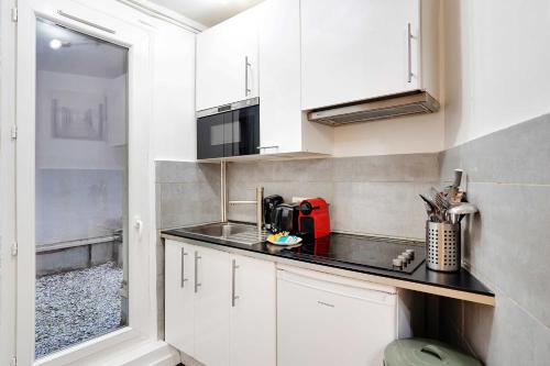 une cuisine avec des armoires blanches et un comptoir noir dans l'établissement Confort et Charme pour 6 à Republioque, à Paris