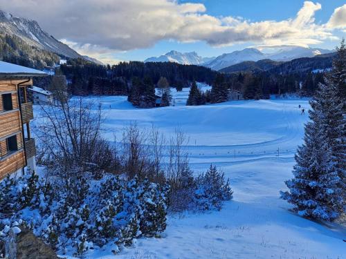 a view of a snow covered field with mountains at Apartment Stgirat Bellaval by Interhome in Valbella