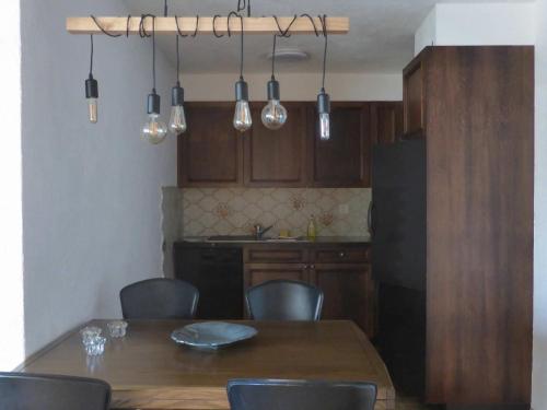a kitchen with a wooden table with chairs and a black refrigerator at Apartment Stgirat Bellaval by Interhome in Valbella