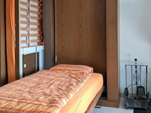 a bed in a room with a wooden door at Apartment Stgirat Bellaval by Interhome in Valbella