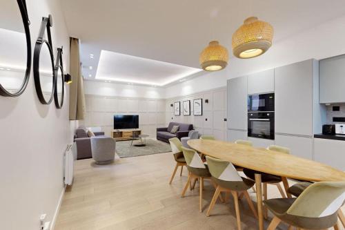 Il dispose d'une cuisine et d'un salon avec une table et des chaises en bois. dans l'établissement Sublime Paris apartment 3Br-10P, à Paris
