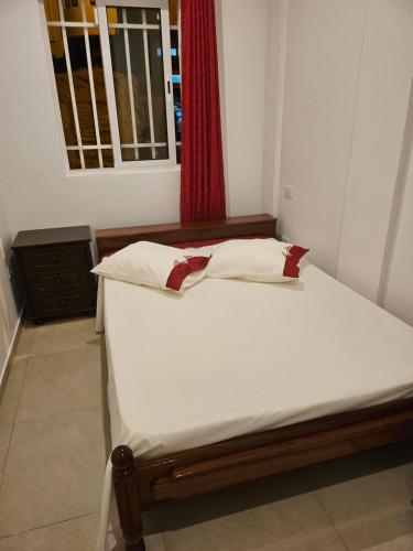 a bed in a room with a red window at Ap ACVA in Mindelo