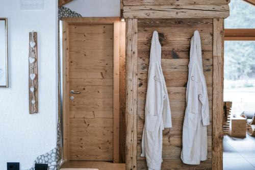 a bathroom with a wooden door and two white towels at Chalet Mornà in San Martino in Badia