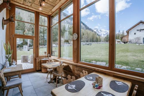 a dining room with large windows and a view of a field at Chalet Mornà in San Martino in Badia