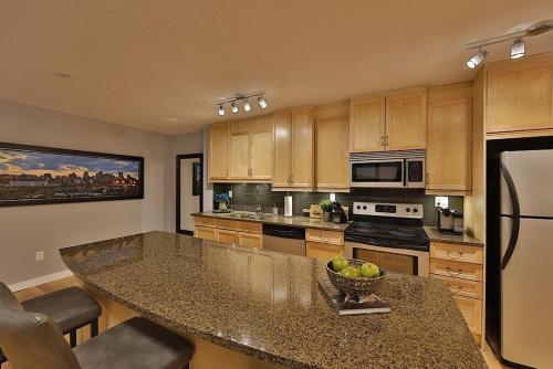 a kitchen with a large island with a bowl of fruit at Ice District 2 Kings Underground Park Patio in Edmonton