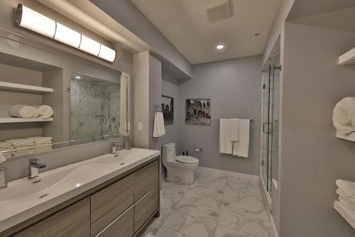 a bathroom with a sink and a toilet and a shower at Ice District 2 Kings Underground Park Patio in Edmonton