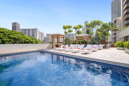 a swimming pool with lounge chairs and a hotel at Luana Waikiki Hotel & Suites in Honolulu