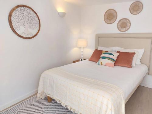 1 dormitorio con cama blanca con almohadas y espejo en Apartment Oceans Window, en Ericeira
