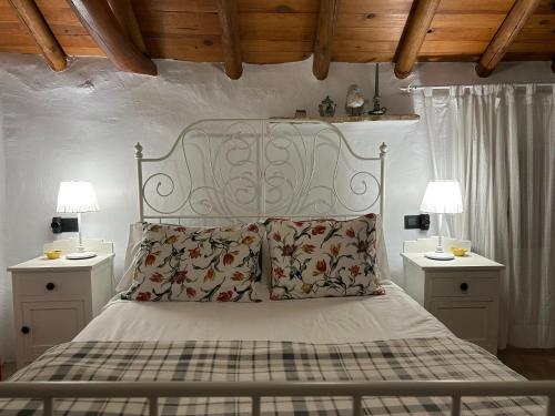 a bedroom with a white bed with two tables and two lamps at Las casillas de la Villa: SOLEÁ in Montefrío